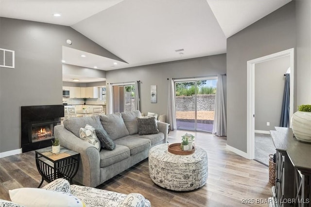 576 Racquet Club Dr Unit 407, Lake Ozark, MO 65049 - living room featuring vaulted ceiling, wood finished floors, recessed lighting, and a lit fireplace