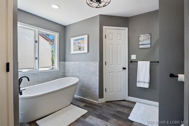 576 Racquet Club Dr Unit 407, Lake Ozark, MO 65049 - bathroom with tile walls, wood finished floors, a soaking tub, and a wainscoted wall