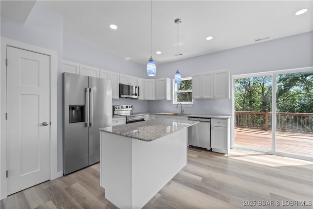 40 Walnut Ct, Eldon, MO 65026 - kitchen with stainless steel appliances, light stone counters, light wood-style floors, white cabinetry, and a center island