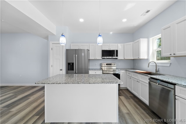 40 Walnut Ct, Eldon, MO 65026 - kitchen featuring appliances with stainless steel finishes, dark wood-type flooring, a center island, light stone counters, and white cabinetry