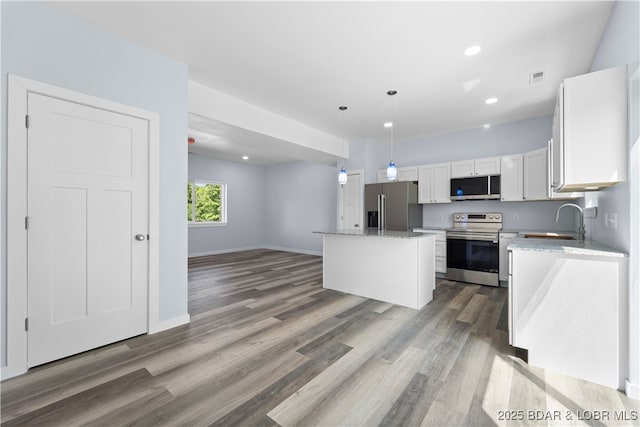 40 Walnut Ct, Eldon, MO 65026 - kitchen with appliances with stainless steel finishes, a kitchen island, wood finished floors, white cabinetry, and recessed lighting
