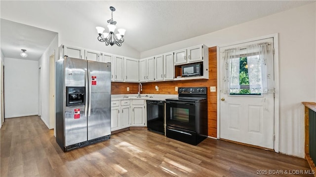 124 Frontier Cir, Linn Creek, MO 65052 - kitchen featuring black appliances, a chandelier, wood finished floors, light countertops, and vaulted ceiling