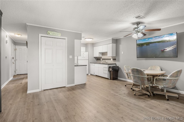 19 Catalpa Ct Unit 2C, Lake Ozark, MO 65049 - dining space featuring a ceiling fan, a textured ceiling, crown molding, and light wood-type flooring