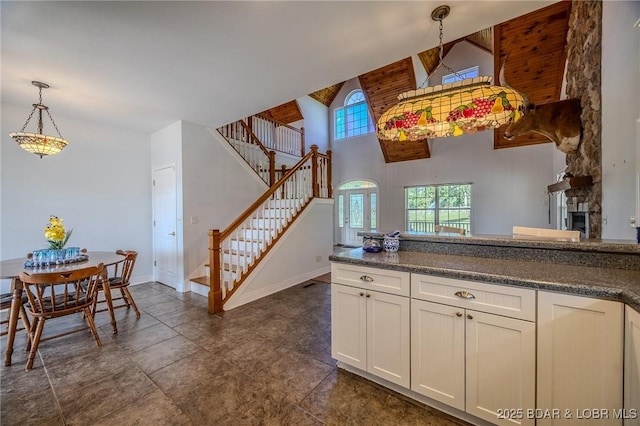 1480 Copperstone Rd, Camdenton, MO 65020 - kitchen featuring high vaulted ceiling, decorative light fixtures, a stone fireplace, dark countertops, and white cabinets