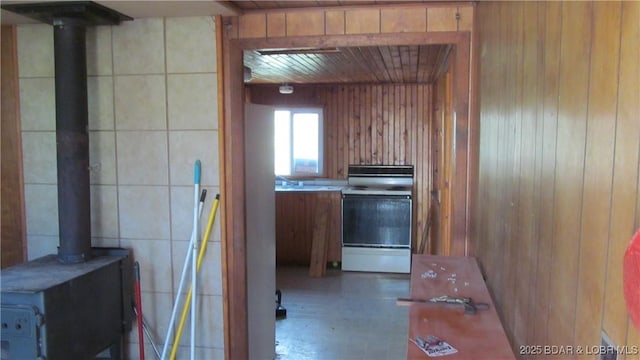 87 Central Ozarks Rd, Edwards, MO 65326 - kitchen featuring electric range oven, a wood stove, wood walls, brown cabinets, and wood ceiling