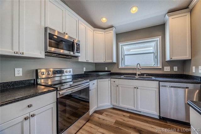 893 Winetavern Rd, Osage Beach, MO 65065 - kitchen with stainless steel appliances, light wood-style flooring, white cabinets, dark countertops, and recessed lighting