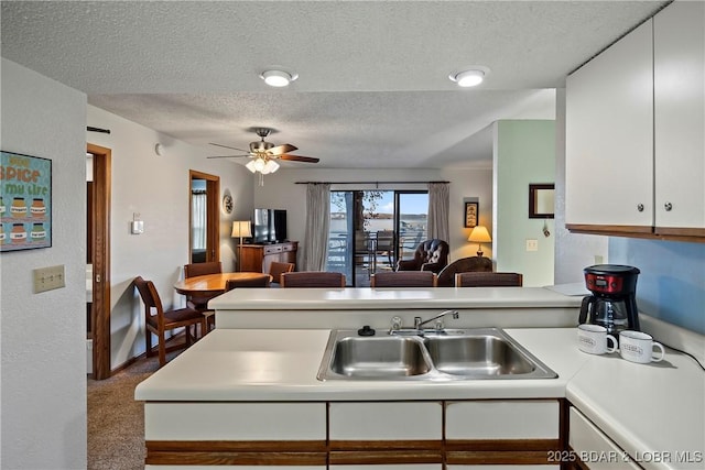 278 Lone Oak Pt Unit 18, Sunrise Beach, MO 65079 - kitchen with a textured ceiling, light countertops, white cabinetry, ceiling fan, and a peninsula