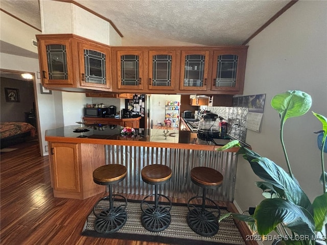 17362 Country Life Rd, Gravois Mills, MO 65037 - kitchen featuring wood finished floors, a textured ceiling, a peninsula, glass insert cabinets, and stainless steel microwave