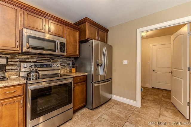 326 Bloomington Dr, Four Seasons, MO 65049 - kitchen with stainless steel appliances, decorative backsplash, light tile patterned flooring, and brown cabinets