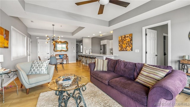 54 Palisades Lakeview Dr Unit 1B, Lake Ozark, MO 65049 - living room with a tray ceiling, light wood finished floors, a ceiling fan, and a chandelier