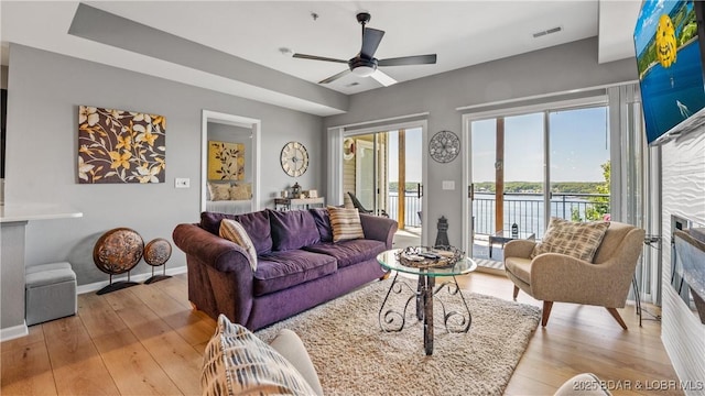 54 Palisades Lakeview Dr Unit 1B, Lake Ozark, MO 65049 - living area with a glass covered fireplace, light wood-style flooring, a ceiling fan, and a water view
