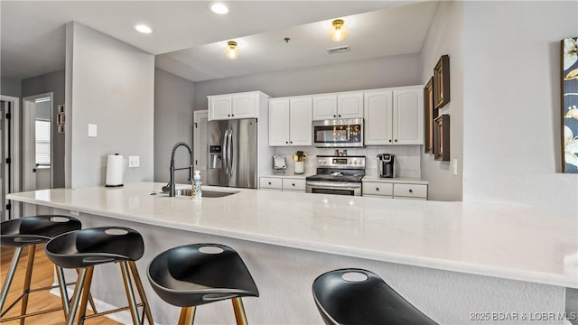 54 Palisades Lakeview Dr Unit 1B, Lake Ozark, MO 65049 - kitchen with stainless steel appliances, a peninsula, white cabinetry, a breakfast bar, and recessed lighting