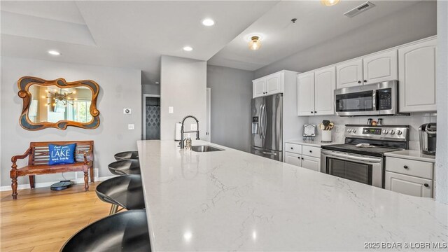 54 Palisades Lakeview Dr Unit 1B, Lake Ozark, MO 65049 - kitchen featuring appliances with stainless steel finishes, light stone counters, white cabinets, recessed lighting, and wood finished floors