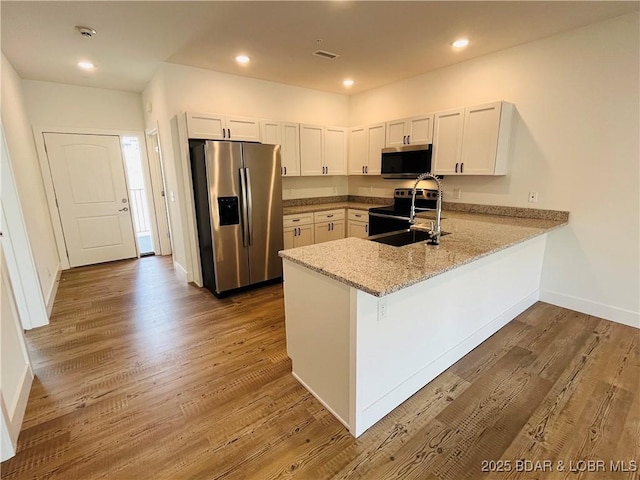 295 Highland Shores Dr Unit 5F, Lake Ozark, MO 65049 - kitchen with stainless steel appliances, a peninsula, wood finished floors, light stone countertops, and recessed lighting