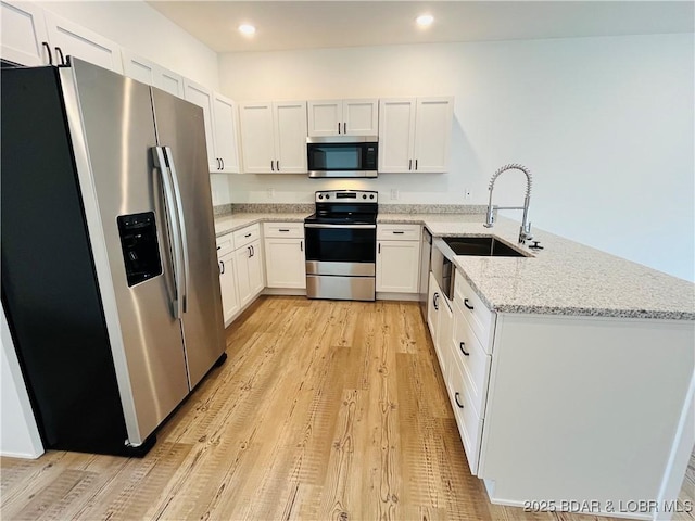 295 Highland Shores Dr Unit 5F, Lake Ozark, MO 65049 - kitchen with appliances with stainless steel finishes, a peninsula, light wood-style floors, light stone countertops, and white cabinetry