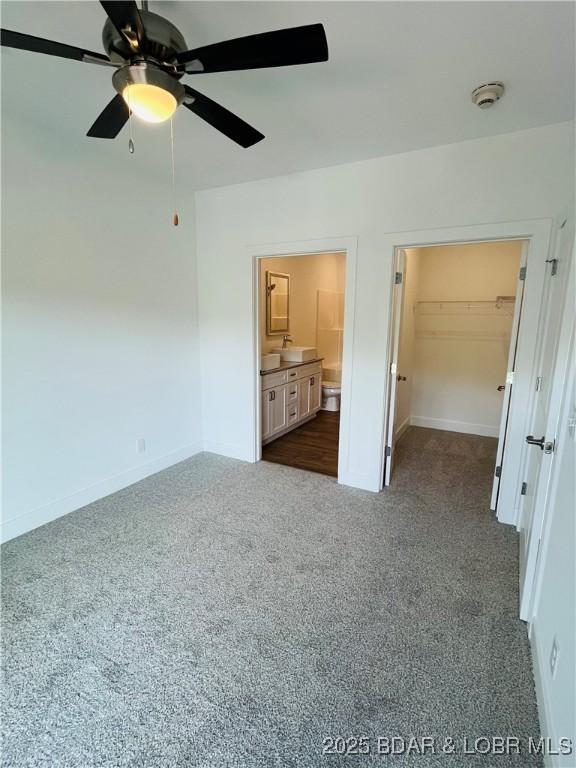 295 Highland Shores Dr Unit 5F, Lake Ozark, MO 65049 - unfurnished bedroom featuring dark carpet, a spacious closet, ensuite bathroom, and ceiling fan