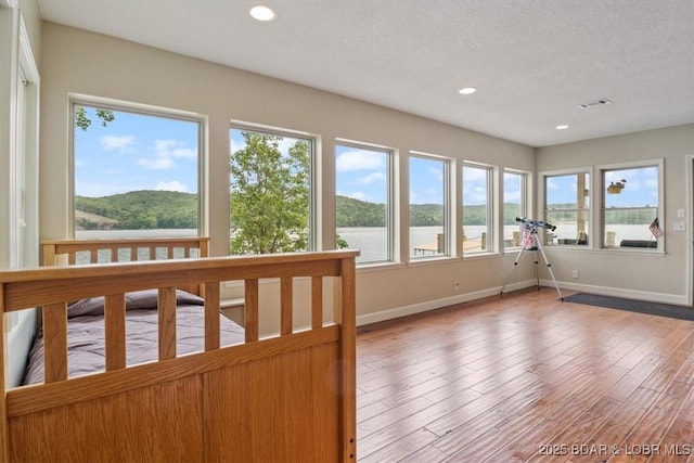 97 Random Rd, Edwards, MO 65326 - unfurnished sunroom with a water view, recessed lighting, wood finished floors, and a textured ceiling