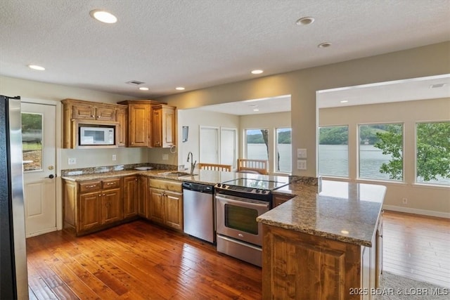 97 Random Rd, Edwards, MO 65326 - kitchen featuring appliances with stainless steel finishes, brown cabinetry, plenty of natural light, a textured ceiling, and recessed lighting