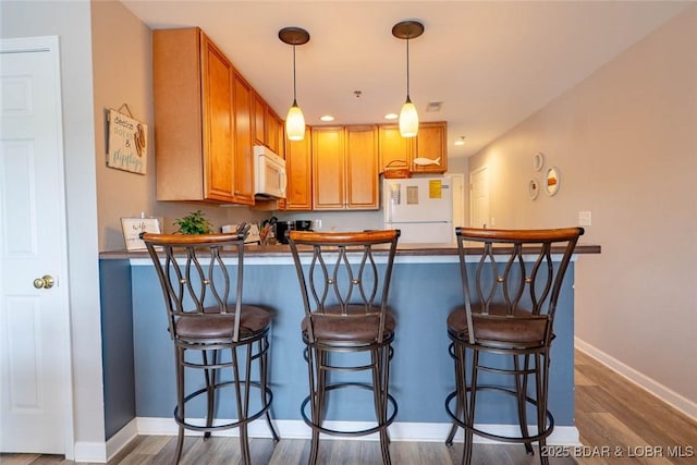 1481 Ledges Dr Unit C24, Osage Beach, MO 65065 - kitchen with white appliances, a peninsula, wood finished floors, decorative light fixtures, and a breakfast bar area