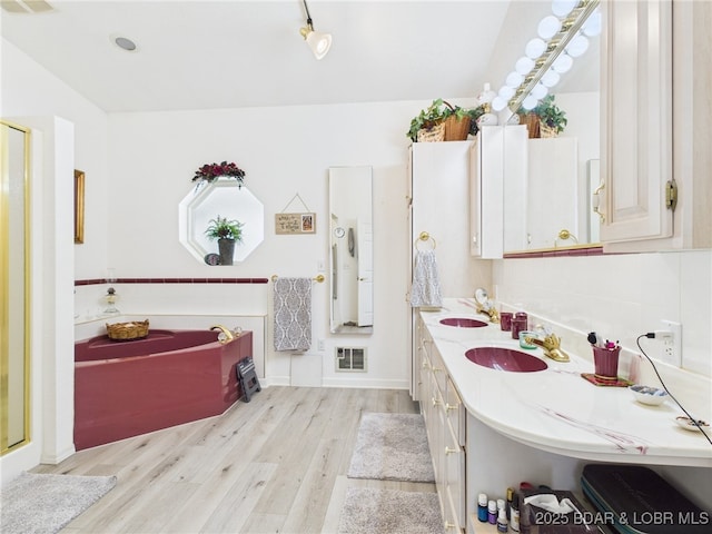 1620 Triple Cove Ln, Climax Springs, MO 65324 - full bathroom featuring wood finished floors, double vanity, lofted ceiling, a garden tub, and a stall shower