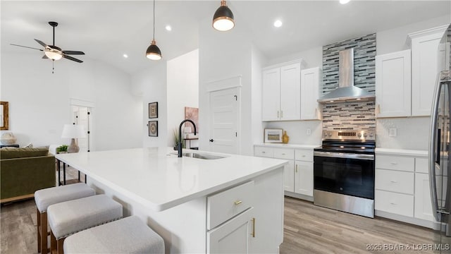 3164 Cross Creek Dr, Camdenton, MO 65020 - kitchen featuring stainless steel electric range oven, wall chimney range hood, open floor plan, backsplash, and light wood-type flooring