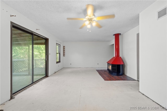 15617 Santa Fe Trl, Gravois Mills, MO 65037 - empty room with concrete floors, a wood stove, a ceiling fan, and a textured ceiling
