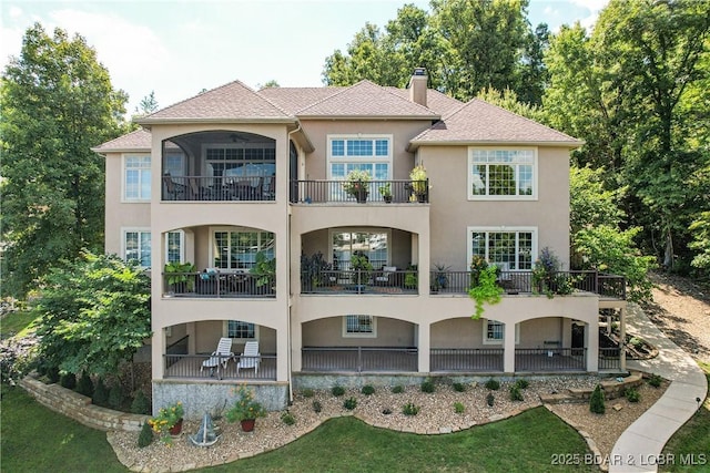 1163 Beacon Pointe Cir, Lake Ozark, MO 65049 - rear view of house featuring stucco siding, a chimney, a balcony, and a patio area