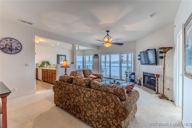 492 Regatta Bay Dr Unit 2D, Lake Ozark, MO 65049 - living room with light carpet, a tile fireplace, and ceiling fan