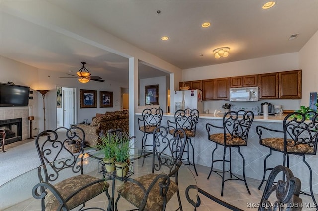 492 Regatta Bay Dr Unit 2D, Lake Ozark, MO 65049 - kitchen with stainless steel microwave, white refrigerator with ice dispenser, a kitchen bar, light countertops, and ceiling fan