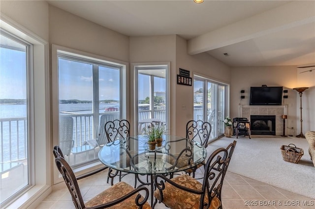 492 Regatta Bay Dr Unit 2D, Lake Ozark, MO 65049 - dining space with light tile patterned flooring, a tile fireplace, light carpet, and beamed ceiling