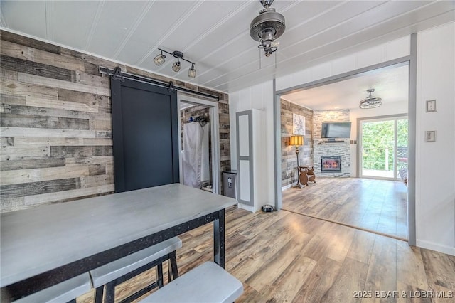 54 White Rock Ln, Sunrise Beach, MO 65079 - dining area featuring light wood-style floors, a barn door, wooden walls, and a fireplace