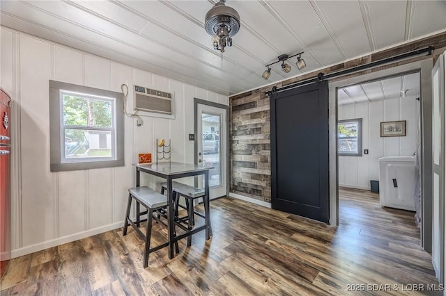 54 White Rock Ln, Sunrise Beach, MO 65079 - dining space featuring a wall unit AC, healthy amount of natural light, a barn door, wood finished floors, and a decorative wall
