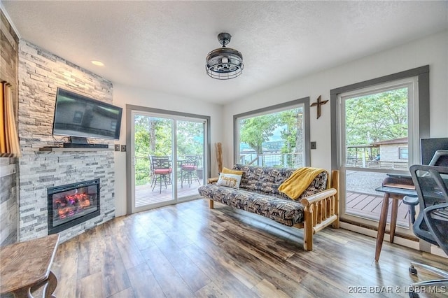 54 White Rock Ln, Sunrise Beach, MO 65079 - living room featuring a textured ceiling, wood finished floors, and a stone fireplace
