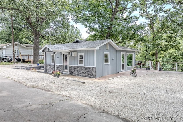 54 White Rock Ln, Sunrise Beach, MO 65079 - view of front of home featuring stone siding, board and batten siding, a shingled roof, and view of wooded area