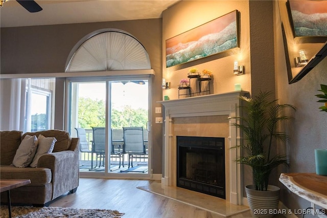 46 Aqua Fin Dr Unit 4A, Lake Ozark, MO 65049 - living room with wood finished floors, a ceiling fan, a fireplace with raised hearth, and a textured wall