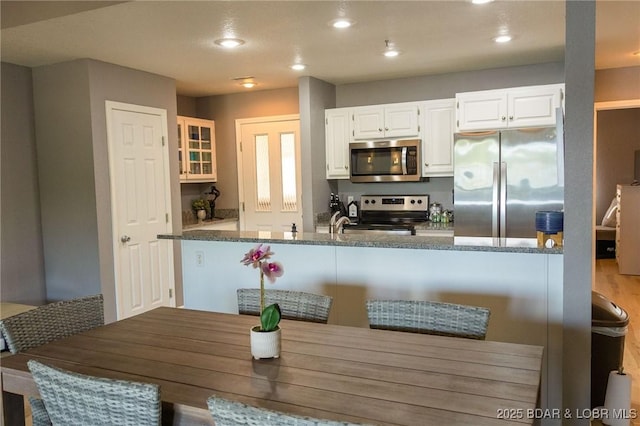 46 Aqua Fin Dr Unit 4A, Lake Ozark, MO 65049 - kitchen featuring appliances with stainless steel finishes, white cabinetry, glass insert cabinets, recessed lighting, and dark stone counters