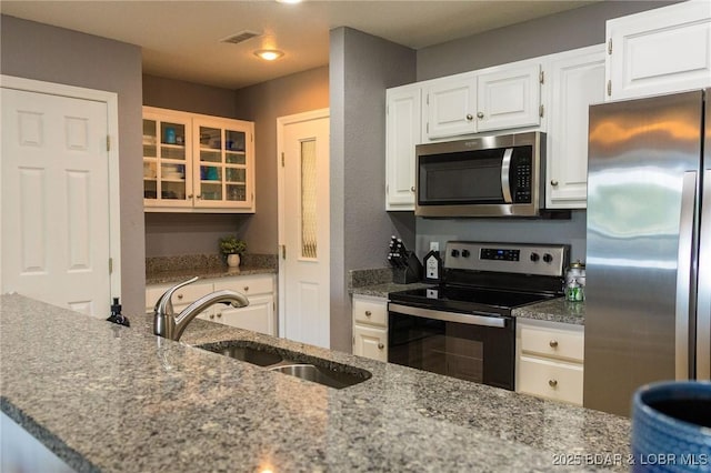 46 Aqua Fin Dr Unit 4A, Lake Ozark, MO 65049 - kitchen featuring appliances with stainless steel finishes, light stone counters, white cabinets, glass insert cabinets, and recessed lighting