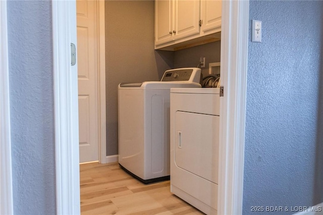 46 Aqua Fin Dr Unit 4A, Lake Ozark, MO 65049 - laundry room with cabinet space, a textured wall, washing machine and dryer, and light wood-type flooring