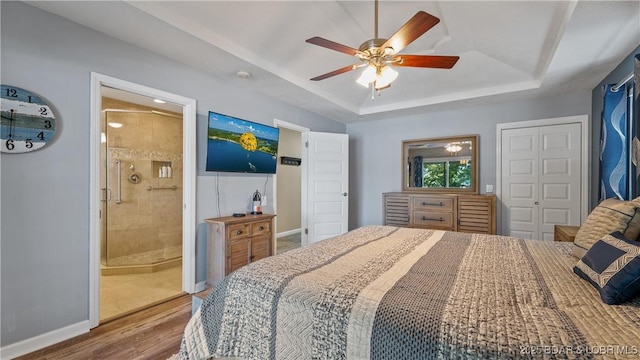 161 Tanglewood Dr, Camdenton, MO 65020 - bedroom with wood finished floors, a raised ceiling, a closet, a ceiling fan, and connected bathroom