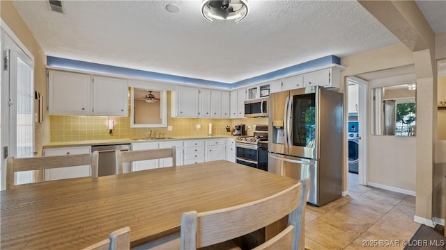 161 Tanglewood Dr, Camdenton, MO 65020 - kitchen with appliances with stainless steel finishes, light countertops, decorative backsplash, washer / clothes dryer, and white cabinetry