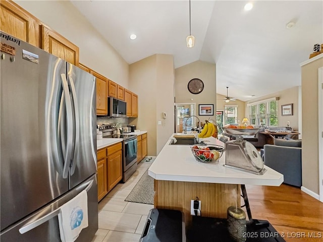 110 Golf View Dr, Camdenton, MO 65020 - kitchen featuring appliances with stainless steel finishes, vaulted ceiling, open floor plan, light countertops, and a center island with sink