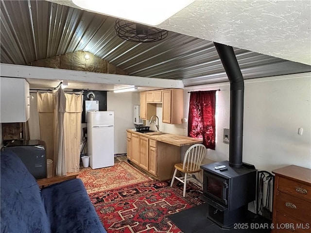 31475 Ivy Bend Rd, Stover, MO 65078 - kitchen featuring freestanding refrigerator, a wood stove, lofted ceiling, butcher block counters, and light brown cabinets