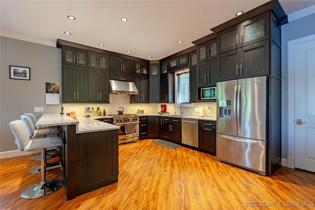 87 Glenmeadows Ct, Linn Creek, MO 65052 - kitchen with stainless steel appliances, exhaust hood, a peninsula, light wood-style floors, and recessed lighting