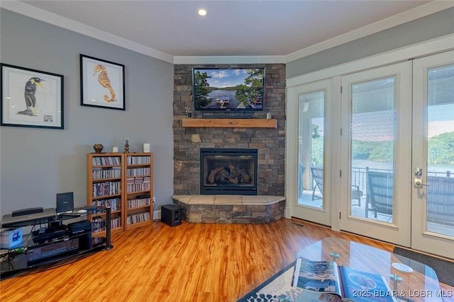87 Glenmeadows Ct, Linn Creek, MO 65052 - living room featuring french doors, wood finished floors, a stone fireplace, and crown molding