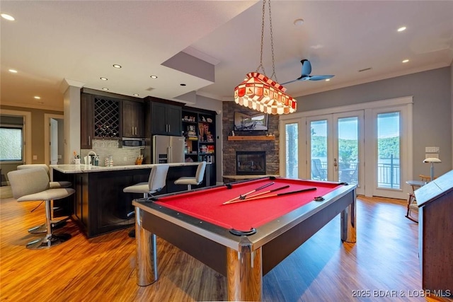 87 Glenmeadows Ct, Linn Creek, MO 65052 - recreation room featuring wet bar, light wood-type flooring, a stone fireplace, recessed lighting, and crown molding