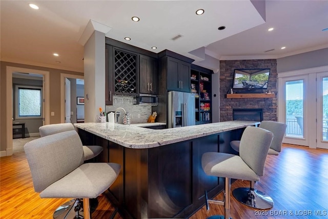 87 Glenmeadows Ct, Linn Creek, MO 65052 - indoor wet bar featuring stainless steel appliances, backsplash, light wood-style floors, ornamental molding, and a stone fireplace