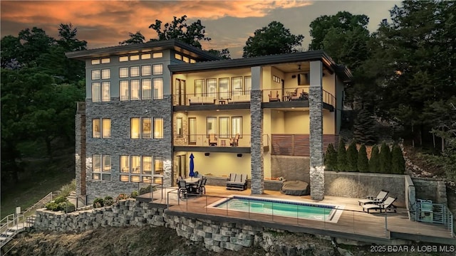 777 Malibu Rd, Osage Beach, MO 65065 - back of property at dusk featuring a balcony, stucco siding, a patio, and stone siding