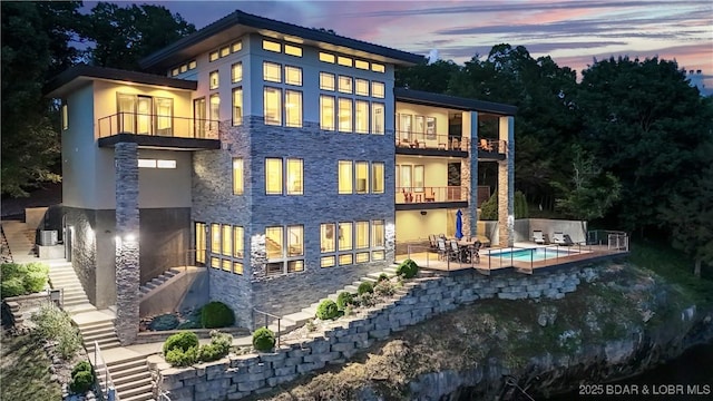 777 Malibu Rd, Osage Beach, MO 65065 - back of house with a balcony, stairs, stone siding, and a patio