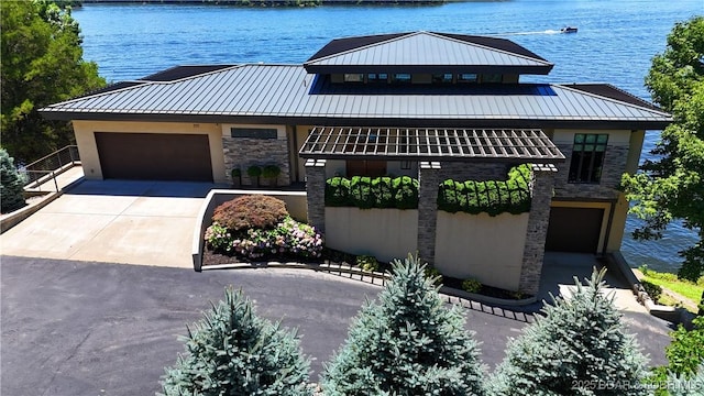 777 Malibu Rd, Osage Beach, MO 65065 - view of front of property with stone siding, concrete driveway, a standing seam roof, and a water view