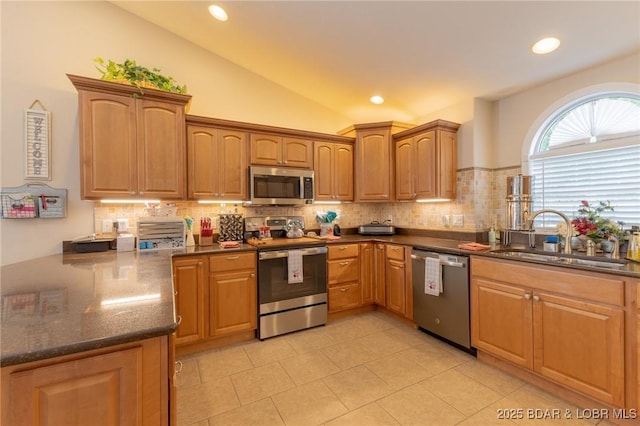 4331 Sunset Dr Unit B, Osage Beach, MO 65065 - kitchen featuring appliances with stainless steel finishes, tasteful backsplash, vaulted ceiling, light tile patterned floors, and dark stone counters